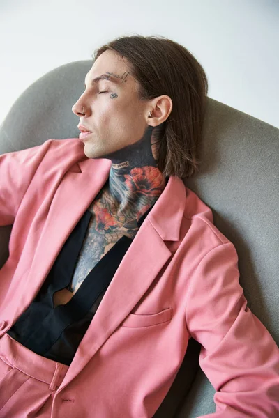 Gut aussehende sexy Mann in stilvollem Outfit Chillen in gemütlichen Stuhl mit geschlossenen Augen, Modekonzept — Stockfoto