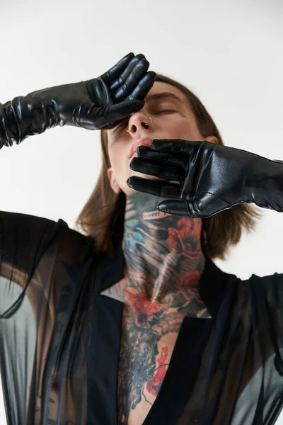 Alluring handsome man in stylish attire with hands in leather gloves on face, fashion concept — Stock Photo