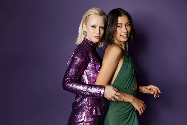 2024 Neujahrsparty, fröhliche multiethnische Freundinnen in festlicher Kleidung vor violettem Hintergrund lächelnd — Stockfoto