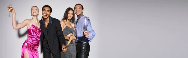 Grupo de amigos inter-raciais felizes segurando champanhe e brilhos, celebrando o banner de Ano Novo — Fotografia de Stock