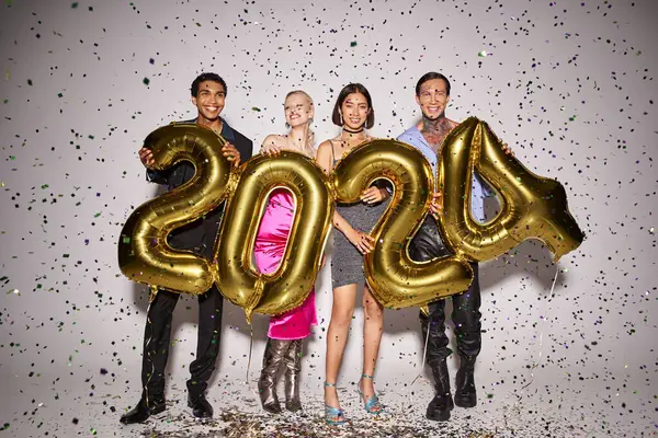 Gioiosi amici multietnici che tengono palloncini con 2024 numeri vicino alla caduta dei coriandoli, festa di Capodanno — Foto stock
