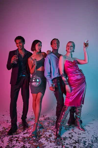 Joyful friends holding champagne glasses and disco ball and celebrating Christmas on purple pink — Stock Photo