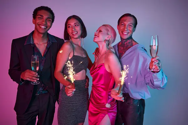 Cheerful multicultural friends holding sparklers and champagne, celebrating Christmas on purple pink — Stock Photo