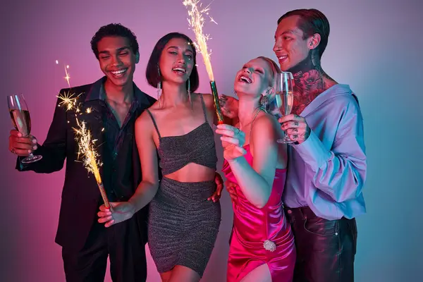 Joyful multiethnic friends holding sparklers and champagne, celebrating Christmas on purple pink — Stock Photo