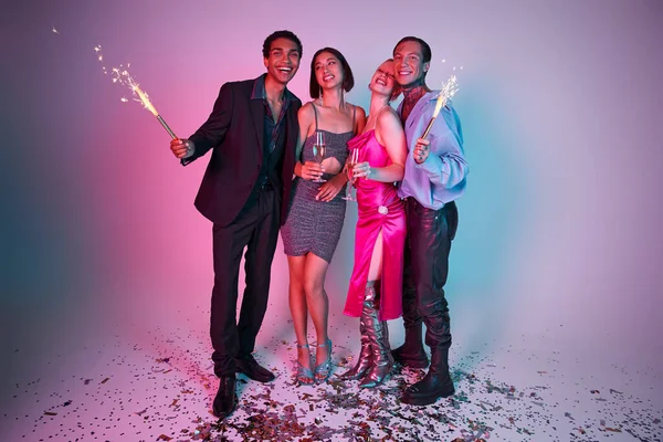 2024 Festa de Ano Novo, amigos multiétnicos positivos segurando sparklers e champanhe em roxo rosa — Fotografia de Stock