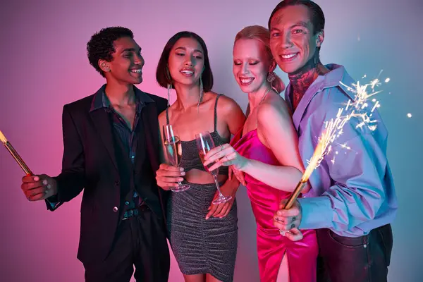 Christmas party concept, radiant multiethnic friends holding sparklers and champagne on purple pink — Stock Photo
