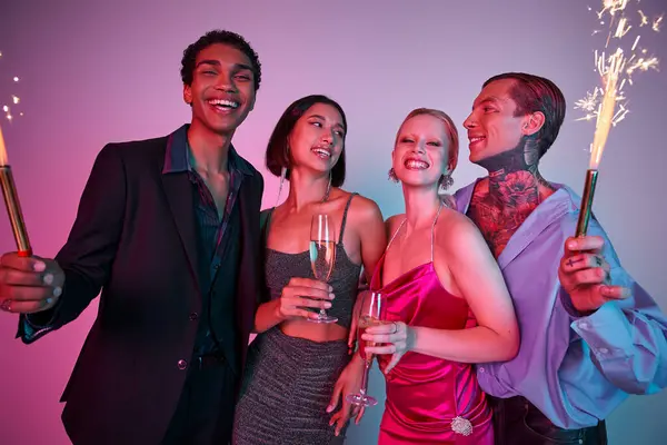 Christmas party concept, joyous multiethnic friends holding sparklers and champagne on purple pink — Stock Photo