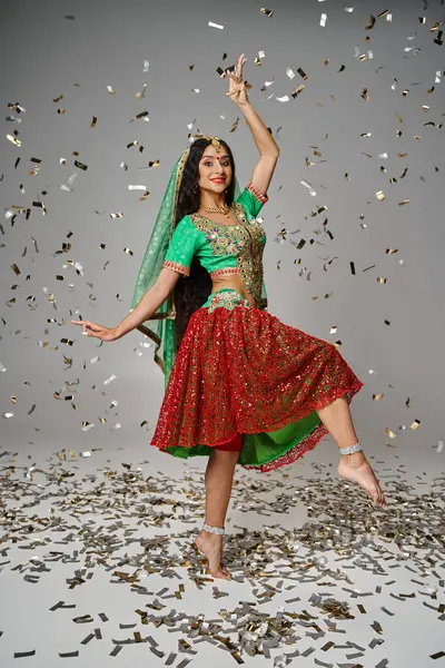 Schöne Indianerin in Tracht posiert in Bewegung unter Konfettiregen und blickt in die Kamera — Stockfoto