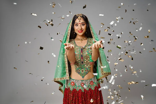 Beautiful indian woman in national clothes with bindi showing open palms and smiling at camera — Stock Photo