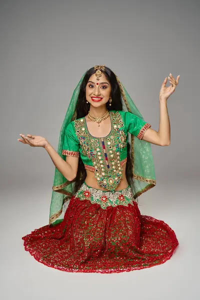 Щаслива молода індійська жінка в червоній спідниці і зелена холі жестикулює і щасливо посміхається на камеру — стокове фото