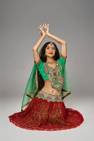 Красивая молодая индианка в традиционной одежде сидит на полу и жестикулирует руками — стоковое фото