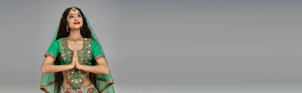 Красивая индийская женщина в национальном костюме с аксессуарами молится и смотрит в сторону, баннер — стоковое фото