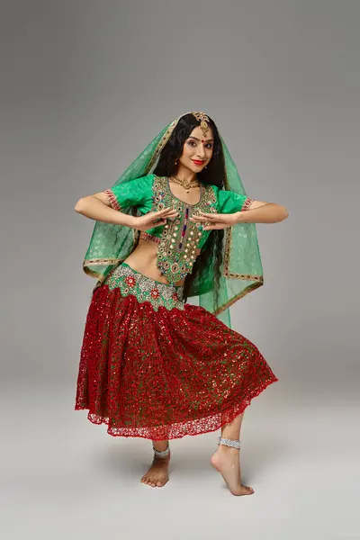 Plan vertical de femme indienne joyeuse avec voile vert et bindi dansant activement et souriant à la caméra — Photo de stock
