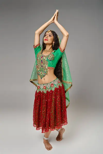Вертикальний знімок індійської красивої жінки в традиційному костюмі танцює активно з піднятими руками — стокове фото