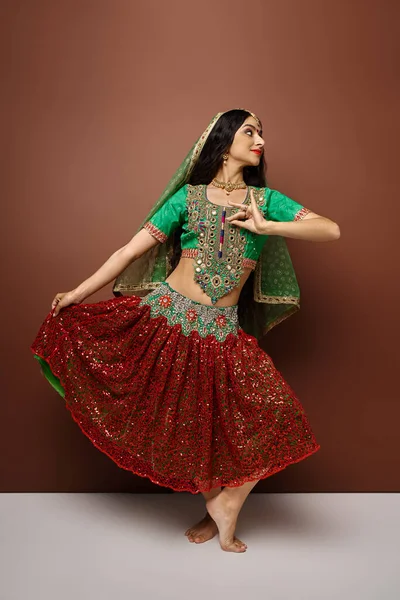Belle femme indienne en tenue traditionnelle avec voile et bindi dansant activement et détournant les yeux — Photo de stock