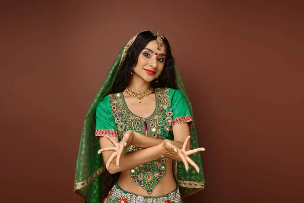 Joyeuse femme indienne aux cheveux longs en costume traditionnel avec accessoires gesticulant avec les mains — Photo de stock