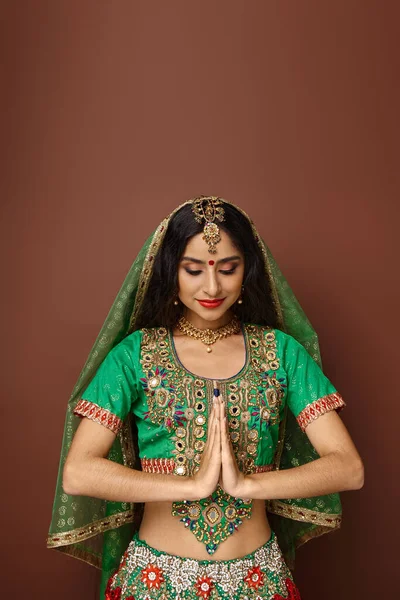 Привлекательная индийская женщина с аксессуарами и бинди точка показывать молитвенный жест и смотреть вниз — стоковое фото