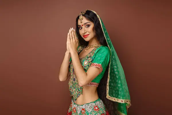 Приваблива молода індійська жінка в національному костюмі, показуючи молитву жестом і посміхаючись на камеру — стокове фото