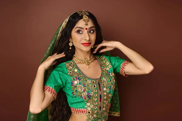 Mujer india alegre bien parecido en traje nacional con velo verde sonriendo y mirando hacia otro lado - foto de stock