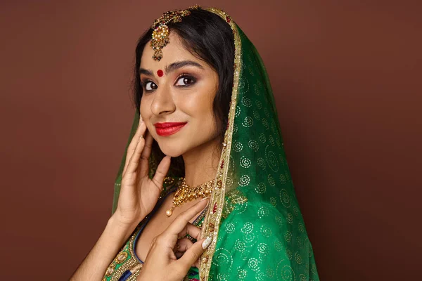 Atractiva mujer india alegre en ropa nacional con bindi dot sonriendo y mirando a la cámara - foto de stock