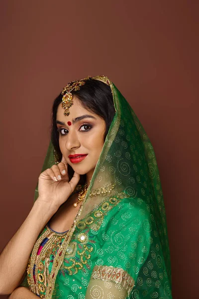 Plano vertical de hermosa mujer india con punto bindi y velo verde posando y mirando a la cámara - foto de stock