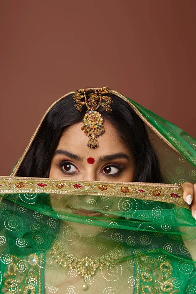 Vertical shot of beautiful indian woman in with bindi dot covering face with veil and looking away — Stock Photo