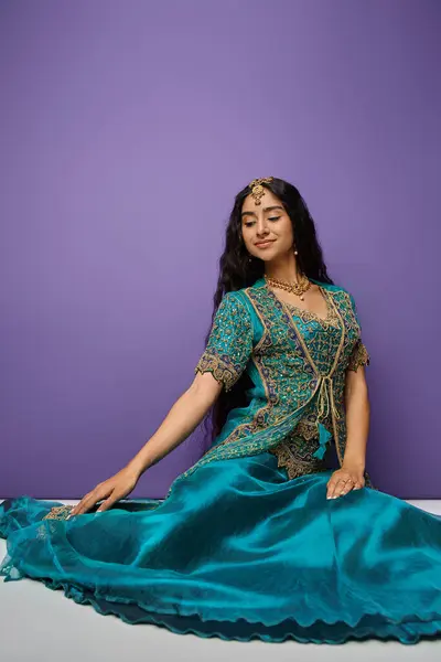 Vertical shot of attractive indian woman sitting on floor in blue traditional sari and looking away — Stock Photo