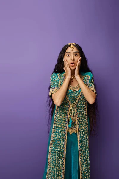 Vertikale Aufnahme einer staunenden indischen Frau im blauen Sari mit Händen in Gesichtsnähe, die schockierend in die Kamera schaut — Stockfoto