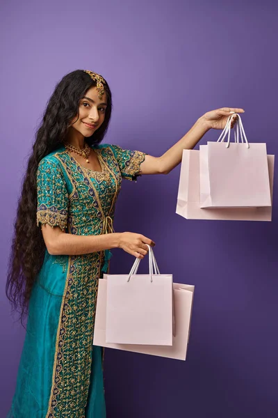 Вертикальний знімок привабливої індійської жіночої моделі в національному костюмі, що тримає сумки в руках — стокове фото