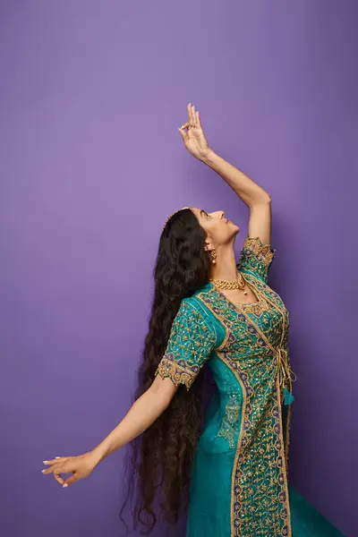 Vertikale Aufnahme einer langhaarigen jungen indischen Frau in Tracht, die beim aktiven Tanzen gestikuliert — Stockfoto