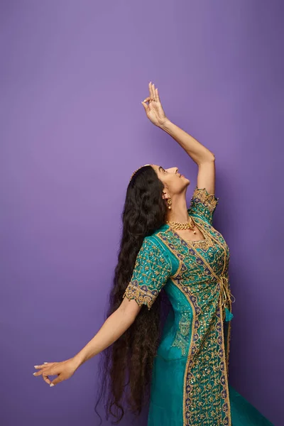 Colpo verticale di giovane donna indiana dai capelli lunghi in costume nazionale gesticolando mentre balla attivamente — Foto stock