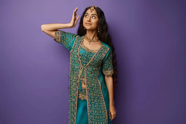 Attractive young indian woman in traditional blue sari with accessories posing on purple backdrop — Stock Photo