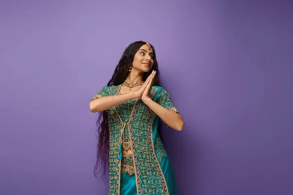 Pretty joyful indian woman in blue sari with accessories posing in motion on purple backdrop — Stock Photo