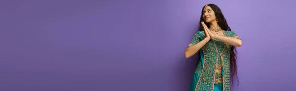 Cheerful indian woman in blue sari with accessories posing in motion on purple backdrop, banner — Stock Photo