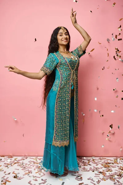 Vertikale Aufnahme einer jungen Indianerin, die beim Tanz im Konfettiregen gestikulierend in die Kamera lächelt — Stockfoto
