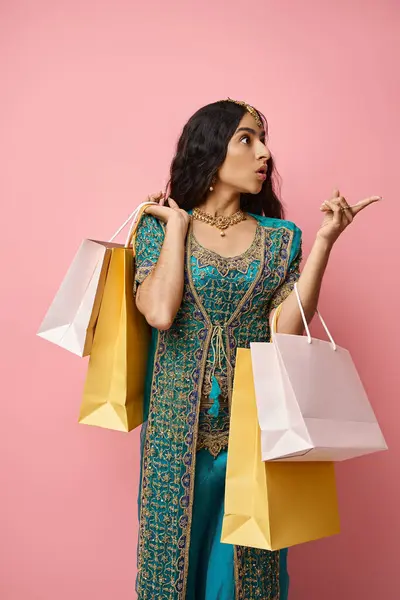Junge überraschte indische Frau in blauem traditionellen Sari posiert mit Einkaufstüten und zeigt weg — Stockfoto