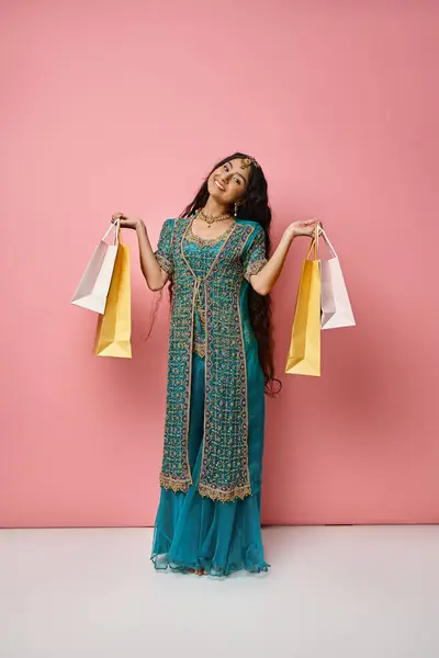 Plan vertical de jeune femme indienne joyeuse en sari bleu posant avec des sacs à provisions souriant à la caméra — Photo de stock