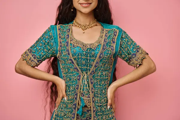 Fröhliche junge indische Frau in Tracht posiert mit den Armen akimbo und lächelt fröhlich, beschnitten — Stockfoto