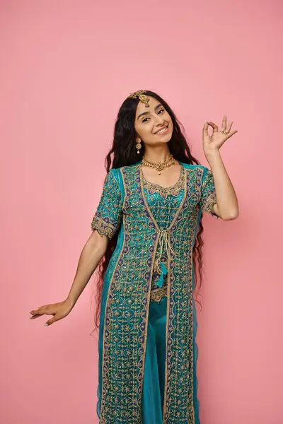 Vertical shot of young indian woman in national costume gesturing and posing on pink background — Stock Photo