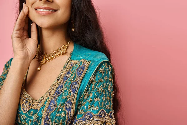 Cheerful indian woman in national costume smiling with hand near face on pink backdrop, cropped — Stock Photo