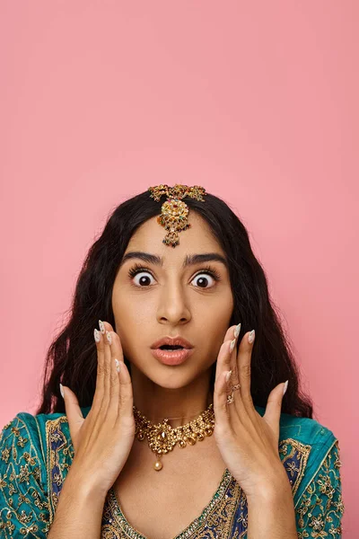 Здивована молода індійська жінка в національному костюмі позує руками біля обличчя з відкритим ротом — стокове фото