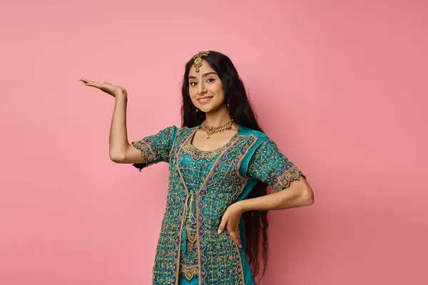 Mulher indiana alegre atraente em roupas tradicionais posando com palma aberta e mão no quadril — Fotografia de Stock
