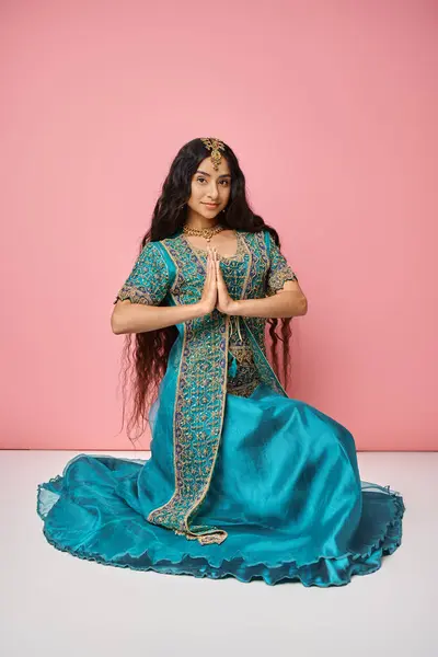 Young beautiful indian woman in traditional blue sari showing praying gesture on pink backdrop — Stock Photo