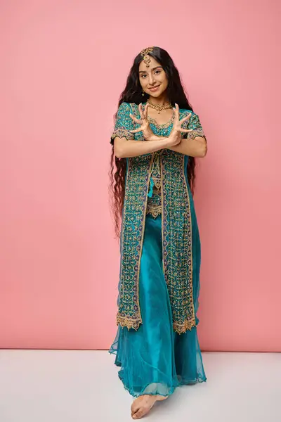 Gut aussehende junge Indianerin in Tracht posiert mit gekreuzten Händen auf rosa Hintergrund — Stockfoto