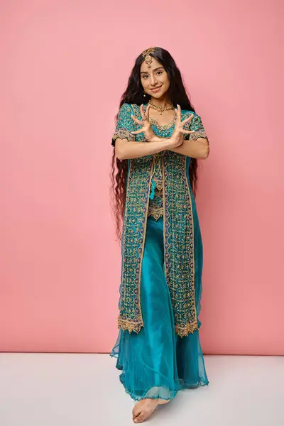 Belle jeune femme indienne en costume national posant avec les mains croisées sur fond rose — Photo de stock