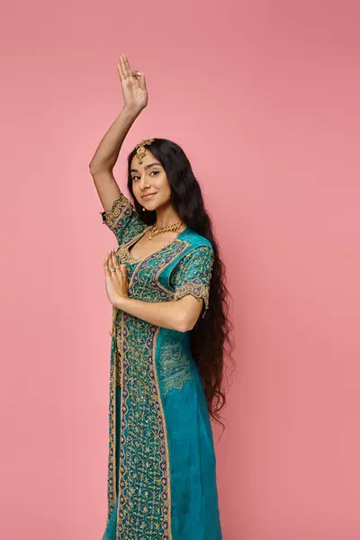Bela mulher indiana em sari azul com acessórios gesticulando no fundo rosa olhando para a câmera — Fotografia de Stock