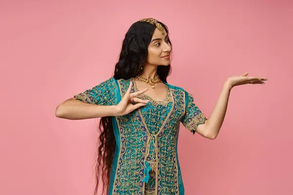 Young attractive indian woman in national costume gesturing and looking away on pink backdrop — Stock Photo