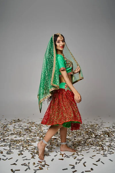 Plano vertical de mujer india joven en ropa nacional con velo y bindi sonriendo a la cámara - foto de stock