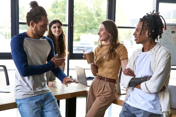 Homme afro-américain parlant à une femme avec tasse en papier lors d'une réunion avec une équipe créative multiethnique — Photo de stock