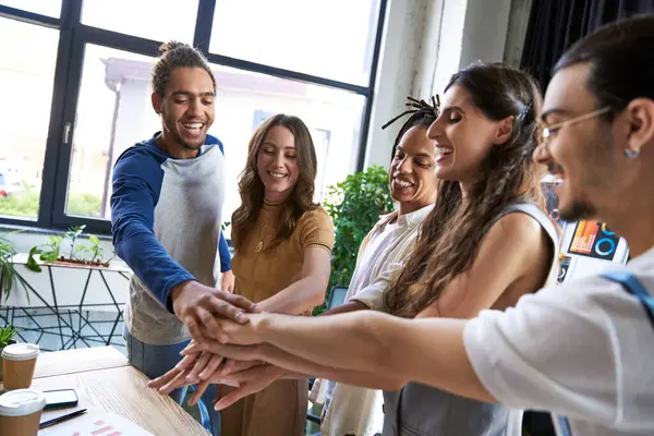 Gioiosa squadra multiculturale mano nella mano come gesto di unità in ufficio moderno, business coworking — Foto stock